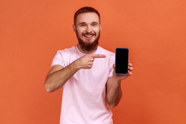 男子指着手机，微笑着对着相机，推荐小工具或移动应用程序。图片下载