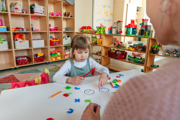 女性心理学家向小女孩展示带有积极和消极情绪的卡片图片下载