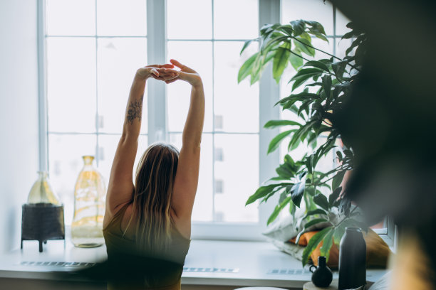 金发女子伸开四肢坐在床上，望着窗外图片下载