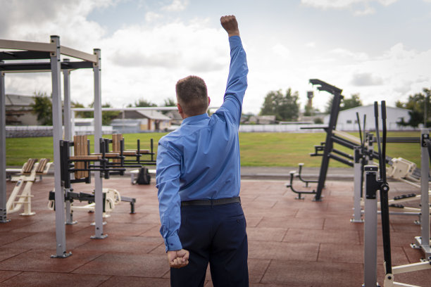 英俊的年轻人穿着黑色西装，白色衬衫和领带在健身房训练图片下载