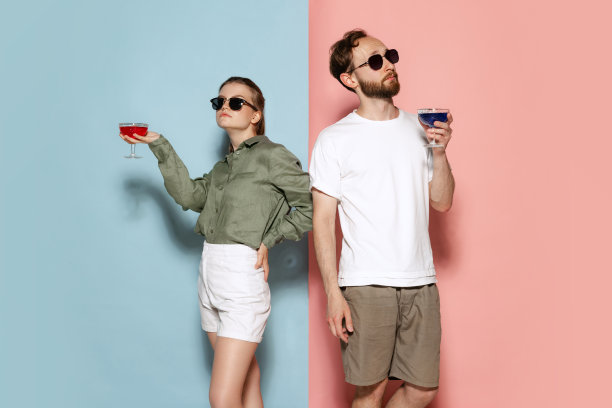 时尚的夫妇，英俊的男子和迷人的女孩摆出孤立的蓝色粉红色的背景。时尚、情感、青春、爱情、旅行、度假概念图片下载