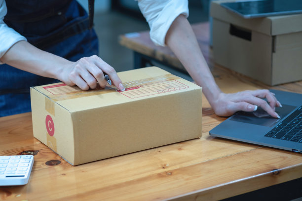 在线销售女企业主接收订单，并将产品与盒子运送给客户。网上中小企业经营理念。图片下载