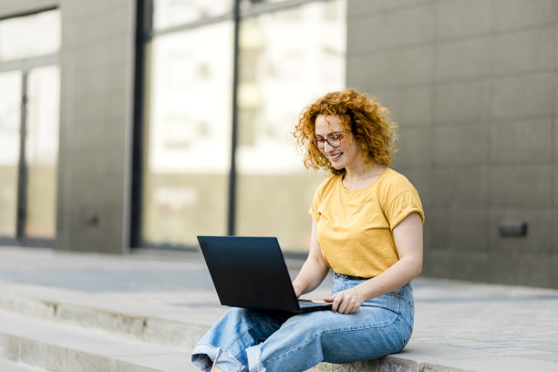 年轻的红发女人在城里用笔记本电脑工作图片下载