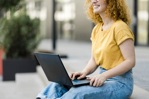 年轻的红发女人在城市里用笔记本电脑工作的特写图片下载