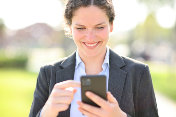快乐的女商人走在外面检查电话图片下载