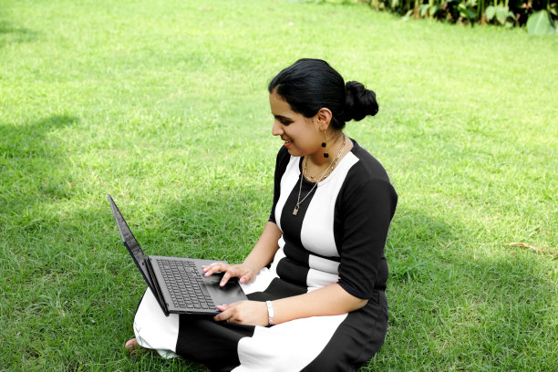 漂亮女孩坐在公园里用笔记本电脑图片下载