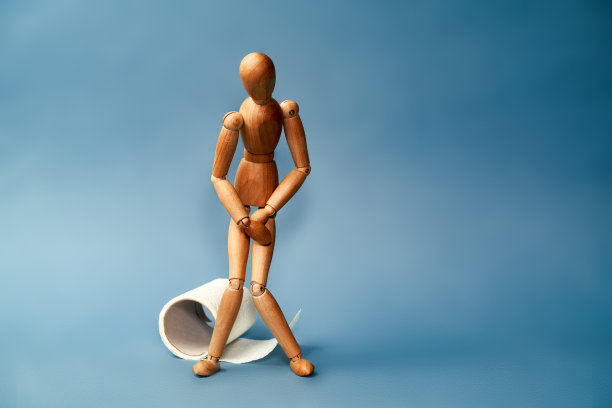 木制雕像站在一卷卫生纸旁边。对问题的概念与消化。图片下载