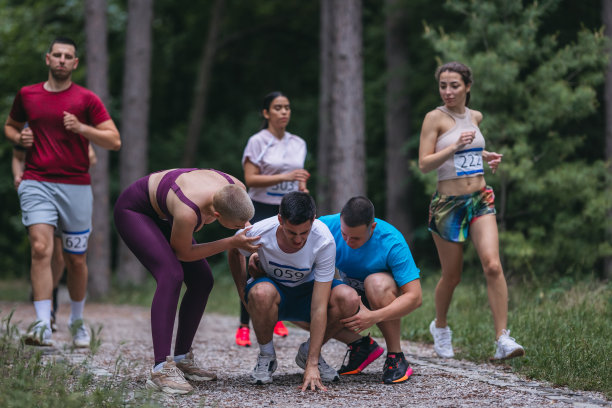 一群运动员在马拉松比赛中帮助受伤的男子图片下载