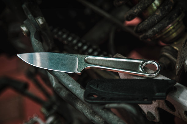 有扳手制成的金属柄的刀工具的武器。背景是摩托车发动机。图片下载