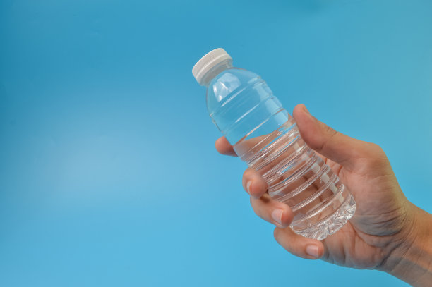 手握矿泉水孤立在蓝色的背景。复制文本空间图片下载