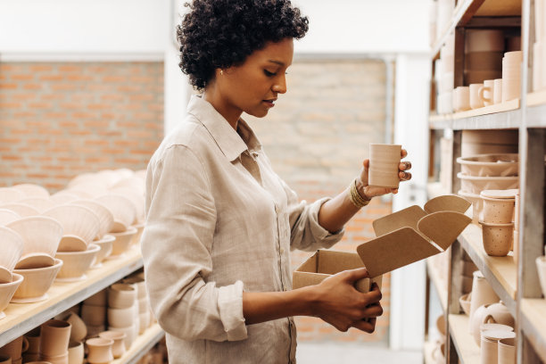 女陶瓷店主包装她的一个陶器产品到一个盒子图片下载