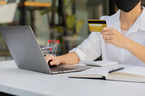 特写照片。亚洲女商人持有信用卡，使用笔记本电脑智能手机检查她的信用卡余额。她根据图表分析了计划。图片下载