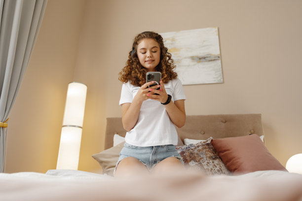 年轻快乐的女人听音乐耳机与智能手机在床上图片下载