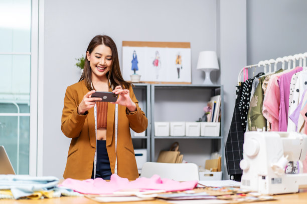 美丽的亚洲女性企业主，时装设计师在服装制作工作室为客户拍摄新服装，概念专业服装设计师图片下载