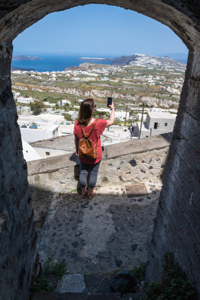 一名妇女在古老的村庄街道上拍照图片下载
