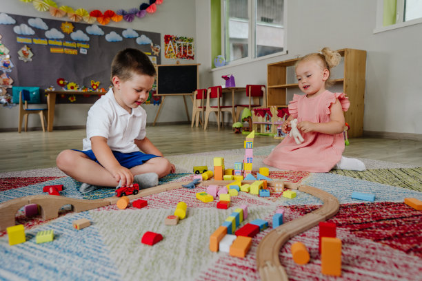 蹒跚学步的男孩和女孩在玩木制火车图片下载