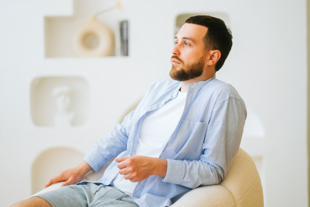 肖像有吸引力的白人男子穿着时尚休闲凝坐在扶手椅。图片下载