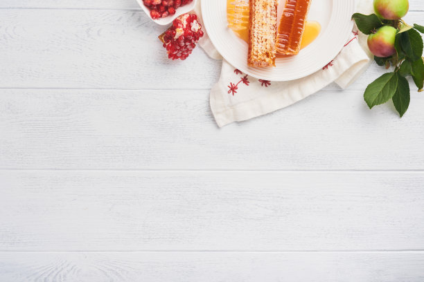 犹太新年。蜂蜜罐，蜂巢，苹果和石榴在白色木制旧质朴的背景表。犹太新年节日贺卡。犹太新年的节日属性。空间的文本图片下载