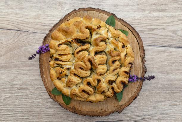 自制的圆形面包，配上蒜蓉黄油和香草，放在有罗勒叶的木板上。图片下载