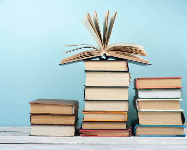 开放式堆叠书，精装彩色书在木桌和蓝色背景。回到学校。复制文本空间。教育事业的概念。图片下载