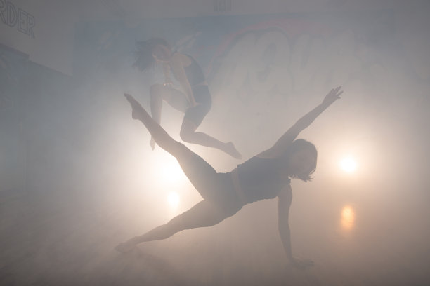 一群多种族的舞者享受时髦的嘻哈移动在黑暗的工作室与烟和照明。一群年轻的街舞舞者在舞台上表演。快乐的跳舞的女人。图片下载