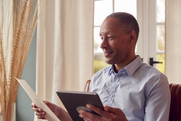 成熟的男人或商人在家工作坐在扶手椅上用数字平板阅读文件图片下载