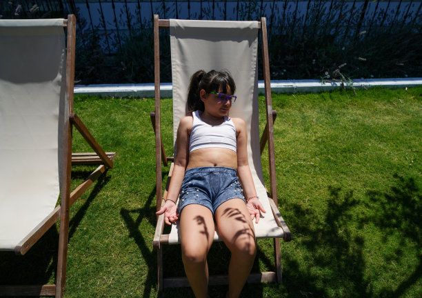 小女孩在花园的椅子上晒太阳图片下载