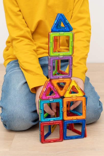 小男孩组装的塔由五颜六色的磁性塑料片搭建而成。图片下载