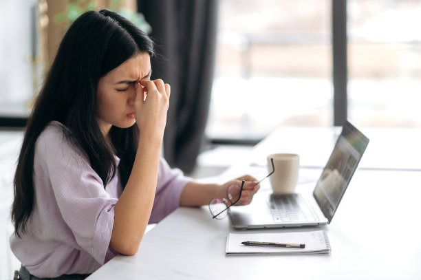 最后期限,劳累的概念。疲惫的亚洲女孩，坐在家里的笔记本电脑前，按摩着她的鼻梁，厌倦了在线工作或学习，已经很久没有休息，需要休息图片下载