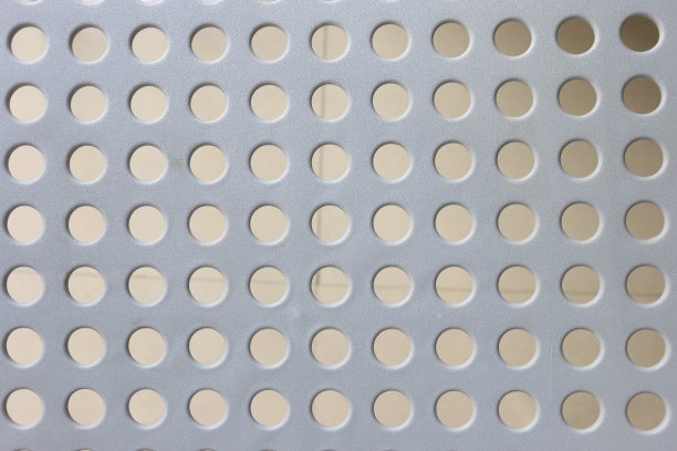 浅灰色表面的圆形小孔有序排列。灰度图像,图片下载