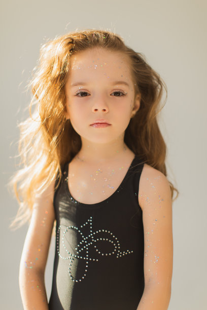 小可爱的女孩与长长的金色卷发在工作室的白色背景。亮片美妆。的童年。时尚的孩子。公主。美丽的脸。的嘴唇光泽图片下载