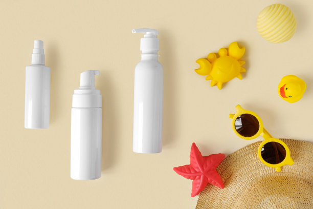 中性背景上的防晒乳管。米色桌子上放着塑料瓶防晒用品和儿童太阳镜和沙盒玩具。儿童护肤理念。对儿童防晒霜。婴儿化妆品。图片下载