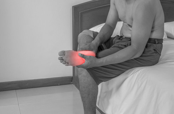 特写一个脚疼的男人，一个男人把手放在脚上，脚部按摩，抽筋，肌肉扭伤和拉伤，脚上红色的口音。医学图像的概念。图片下载