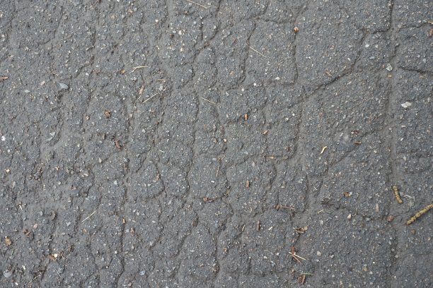 背景:旧的湿沥青，有许多裂缝图片下载