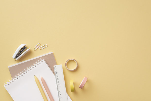 学校附件的概念。俯视图照片的学校用品，记事本，尺子，钢笔，夹子，迷你订书机和胶带在孤立的粉彩黄色背景与copyspace图片下载