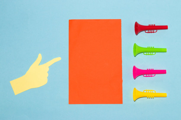 橙色的纸作为复制空间，旁边是彩色的小号和手指指向纸，通知，蓝色背景上的创意艺术设计图片下载