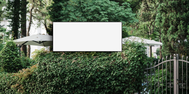 酒店入口附近的绿色灌木丛上固定着一块空白的标牌图片下载