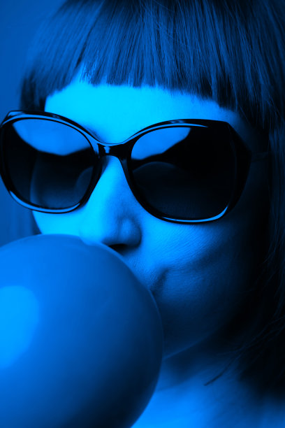 戴墨镜的女人吹着口香糖泡影图片下载