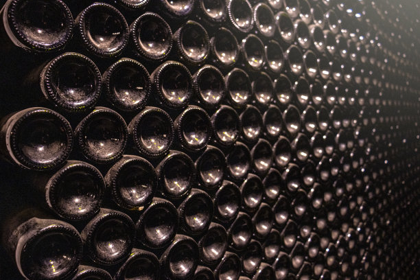 质感的红酒酒瓶堆放在酒窖中。水平的观点。图片下载