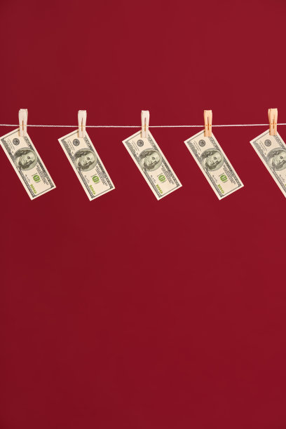洗钱，用绳子吊着的美元挂在红色的演播室背景上图片下载
