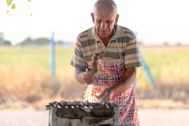 一位老人在后院为他的家人做烧烤图片下载