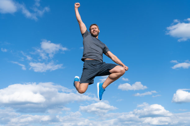 穿着运动服的肌肉男在天空背景下跳跃，成功了图片下载