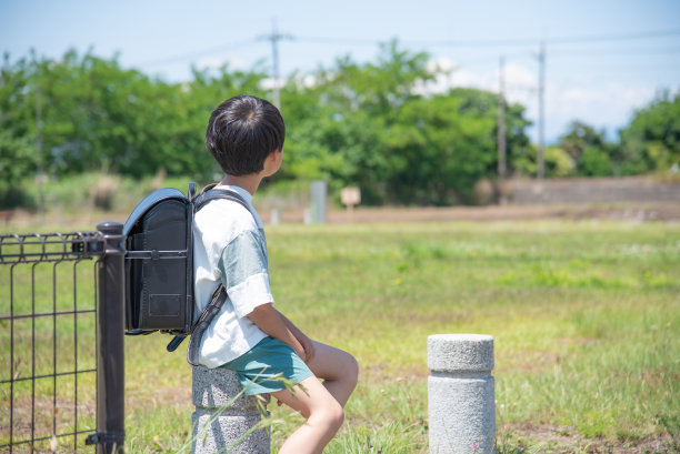 一个小学男孩在放学回家的路上停在公园里图片下载