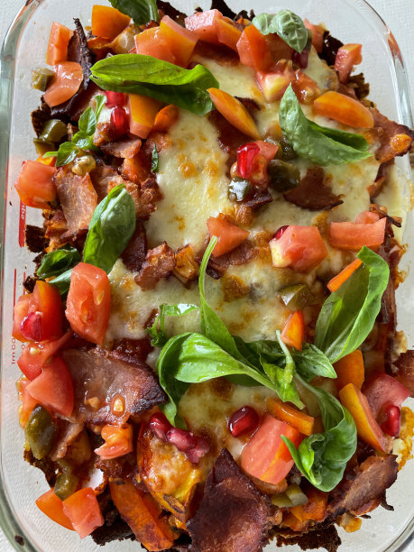 装满玉米片的图片，上面覆盖着自制的番茄莎莎酱和融化的马苏里拉奶酪，上面放着切碎的番茄、培根片、石榴籽和罗勒，玻璃，可保温的盘子，随时可以吃，景色宜人图片下载