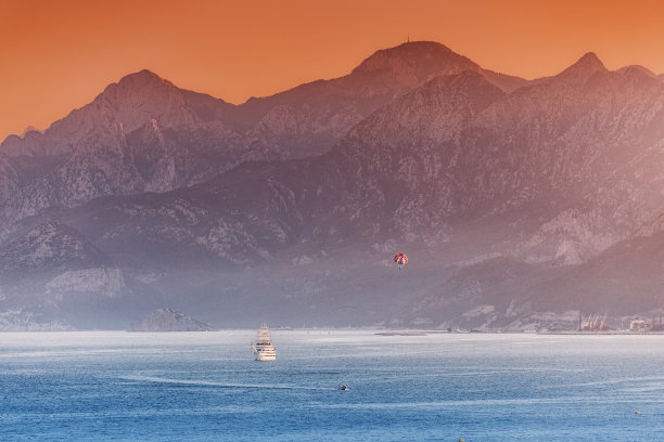 远处缩放的游轮和水上运动降落伞与雄伟的金牛座山脉在安塔利亚地区在土耳其图片下载