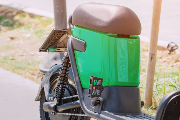 停在城市公园的电动滑板车或带电池的环保自行车。现代交通的概念图片下载