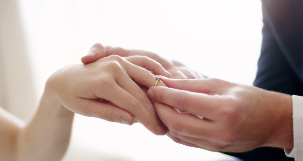 婚姻，戒指和爱之间的丈夫和妻子在他们的仪式上交换结婚戒指。浪漫的男子牵着女子的手求婚，并在答应后赠送订婚戒指图片下载