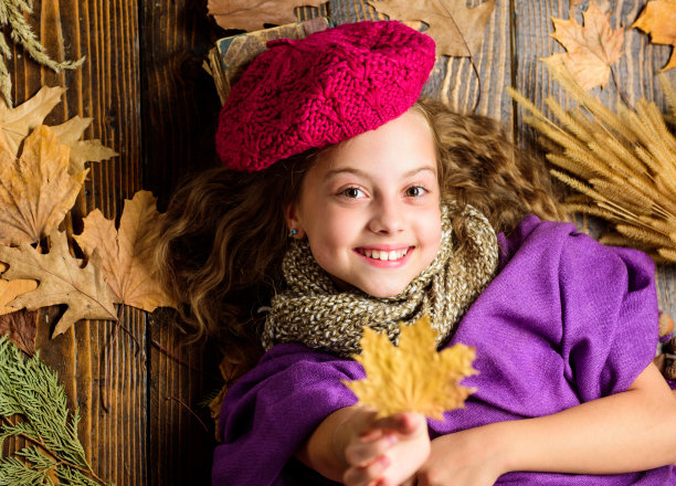 针织配饰时尚细节。小女孩明亮柔软的针织帽贝雷帽。秋季时尚针织配饰。秋季流行针织帽。少女卧木背景落叶俯视图图片下载