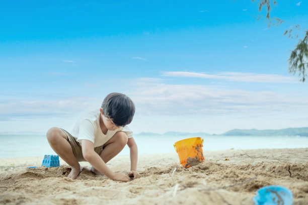 亚洲小孩在夏天的沙滩上玩沙子和放松。假日的户外活动和生活方式。图片下载