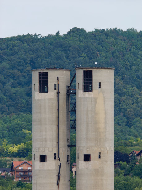 两个高大的旧工厂烟囱的垂直照片，以山和天空为背景图片下载